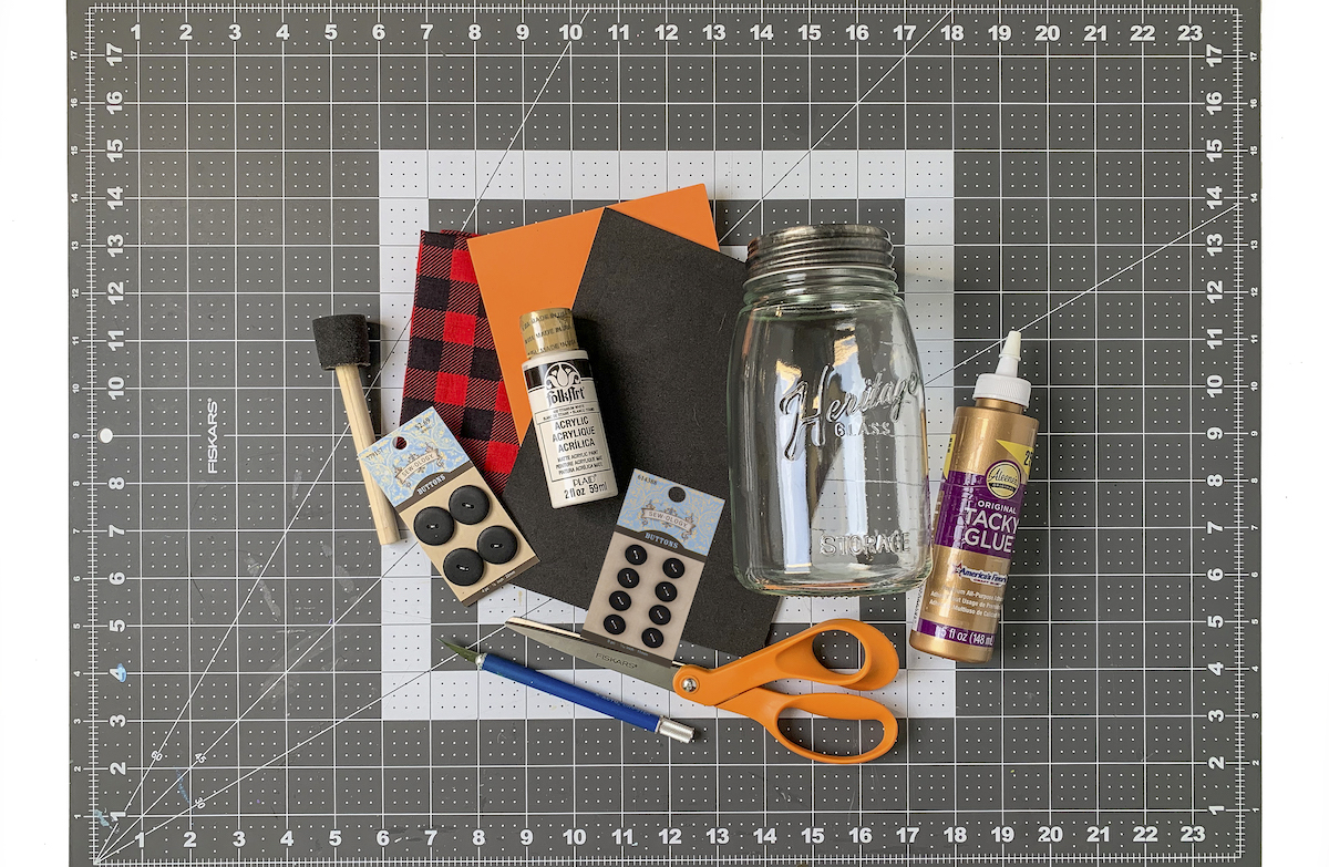 Buffalo plaid bandana, orange craft foam, black craft foam, mason jar, tacky glue, white multisurface paint, black buttons scissors,