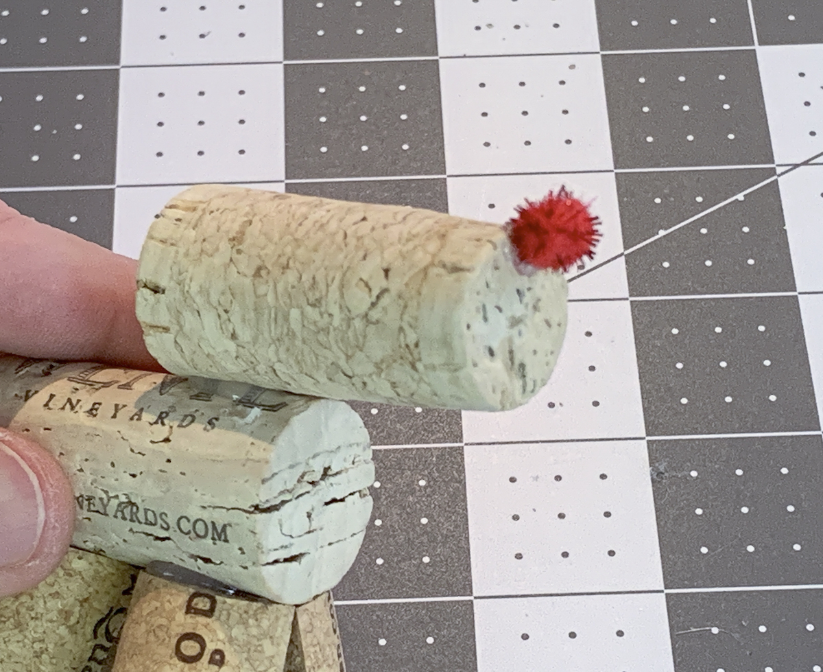 Red pom pom glued to the end of a wine cork to make a reindeer