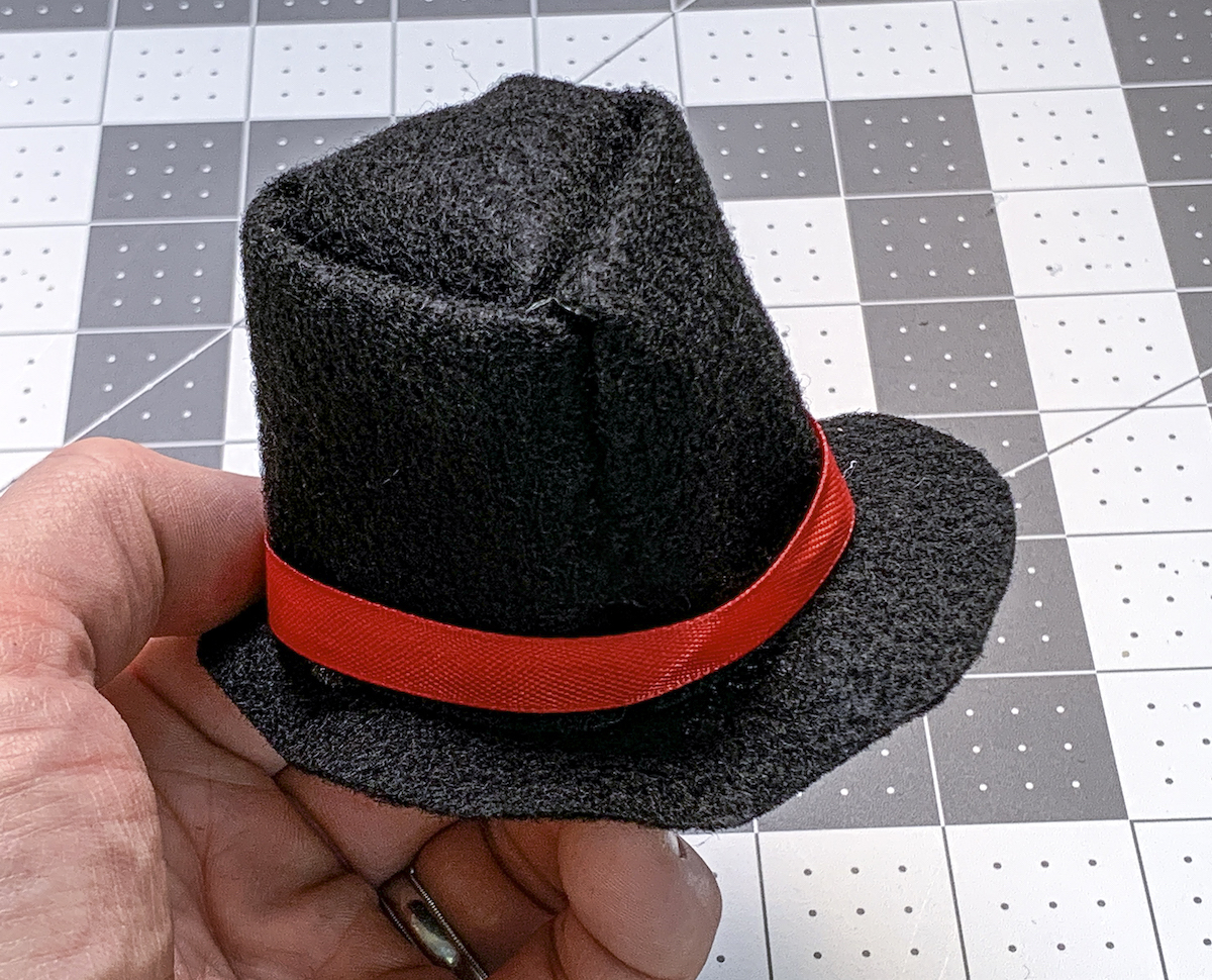 Red ribbon glued around the band of a black felt snowman hat