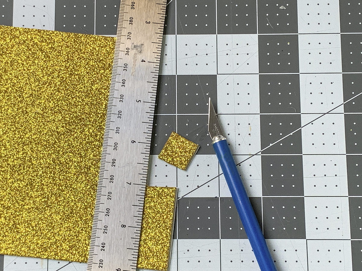 Square cut out of gold glitter foam and a craft knife