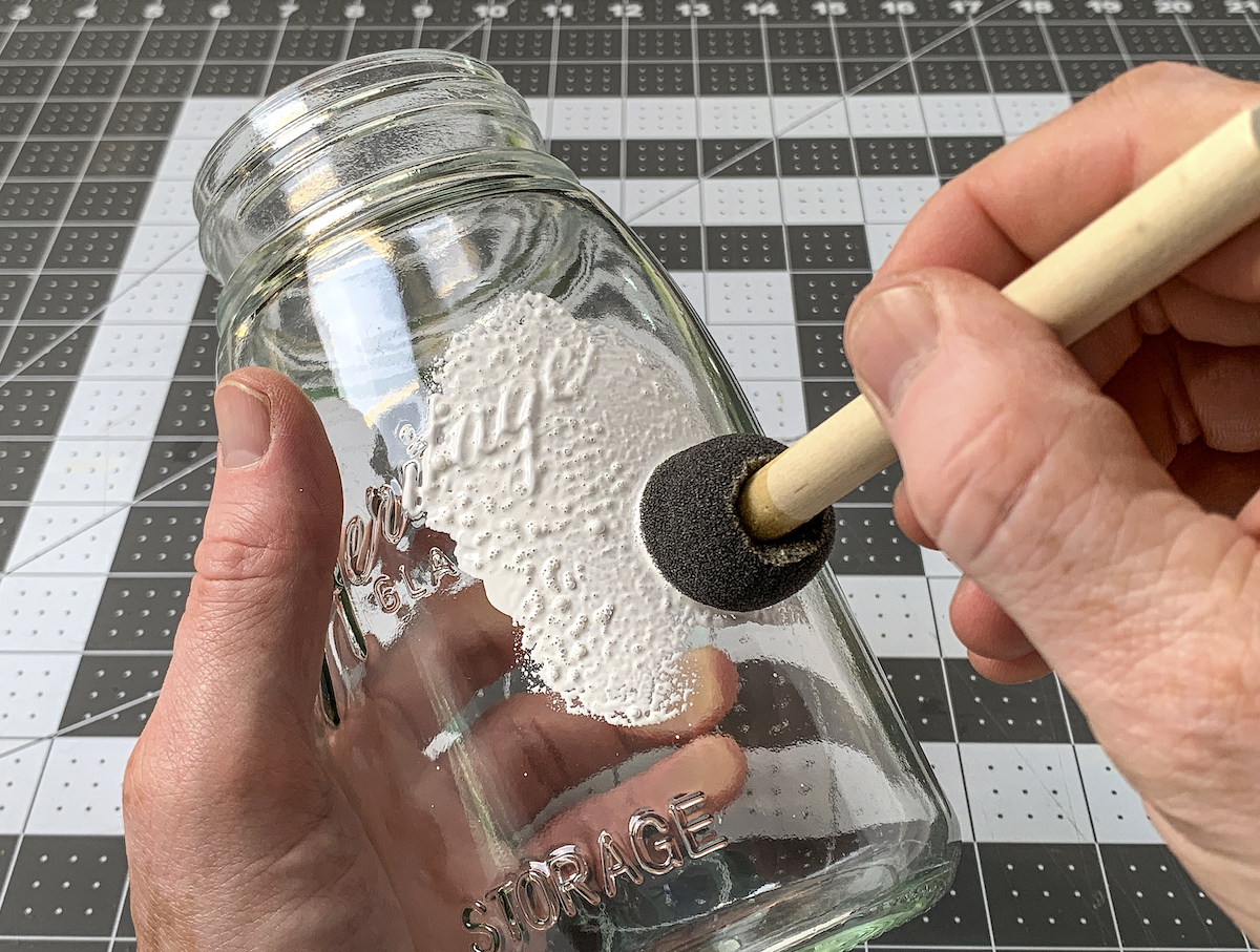 White paint being applied to a jar with a spouncer