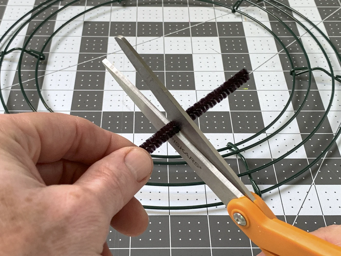 Cutting a black pipe cleaner with a pair of scissors