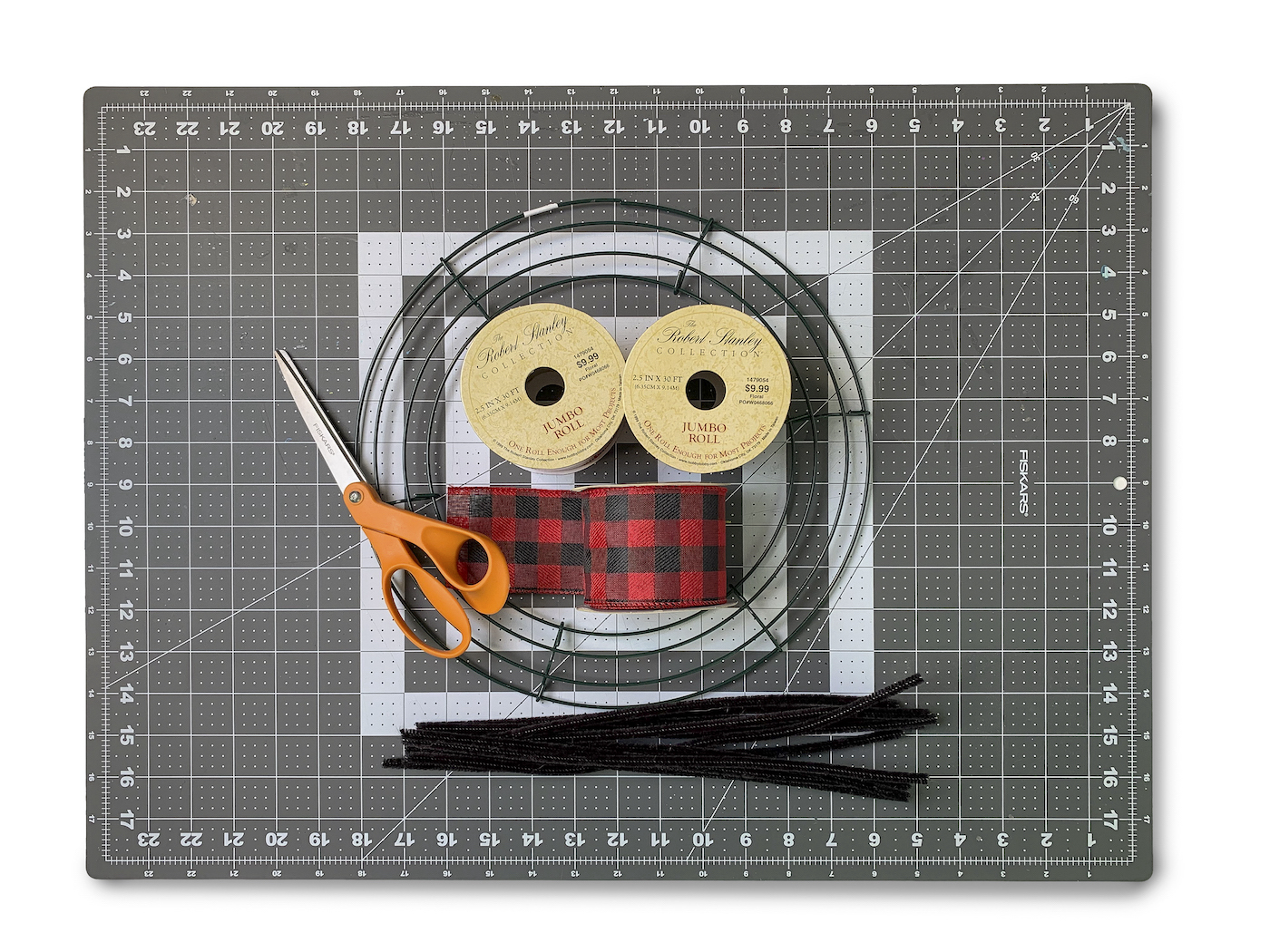 Wire wreath form, scissors, buffalo plaid ribbon, and pipe cleaners