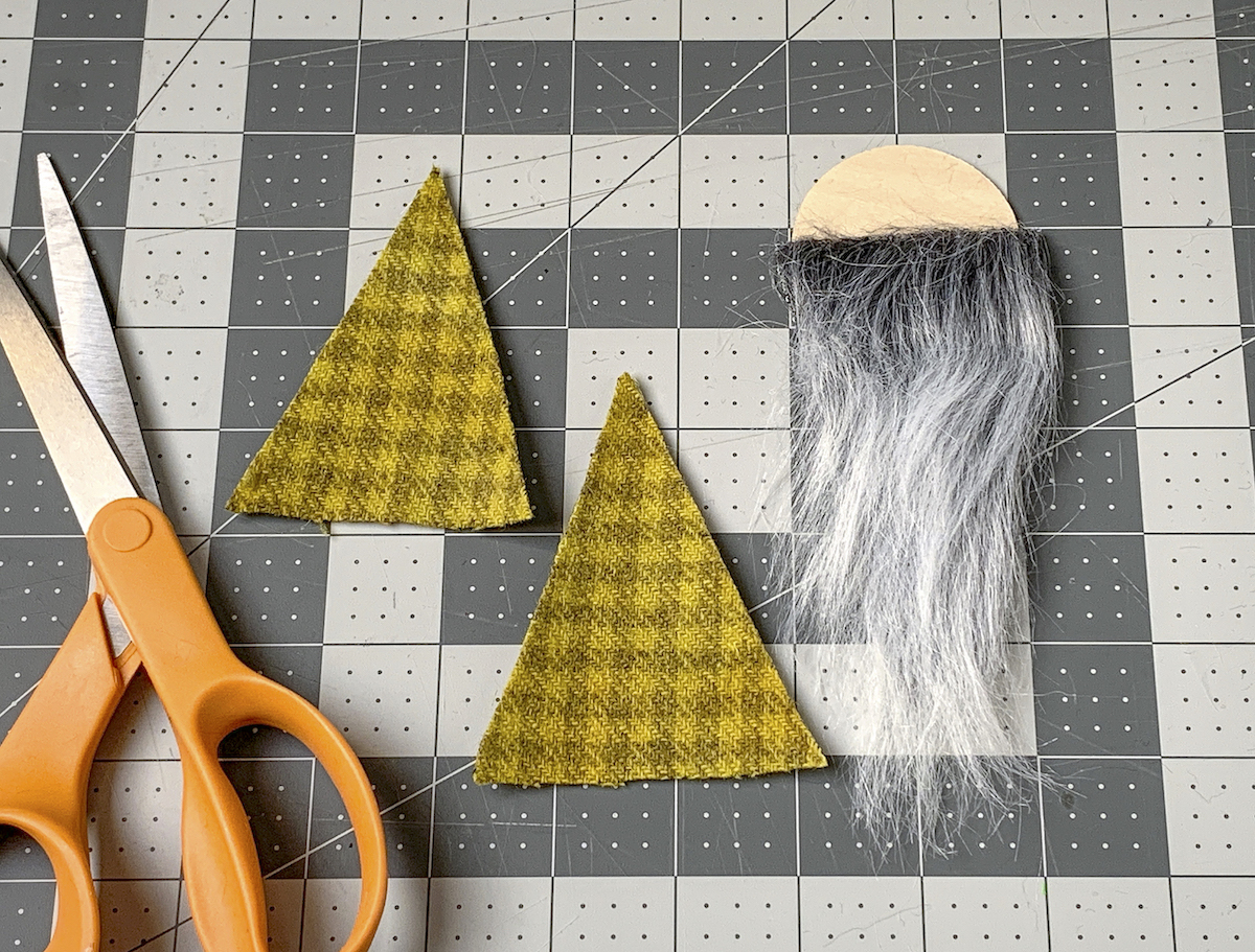 Pair of scissors, two felt triangles, and a wood circle with faux fur attached