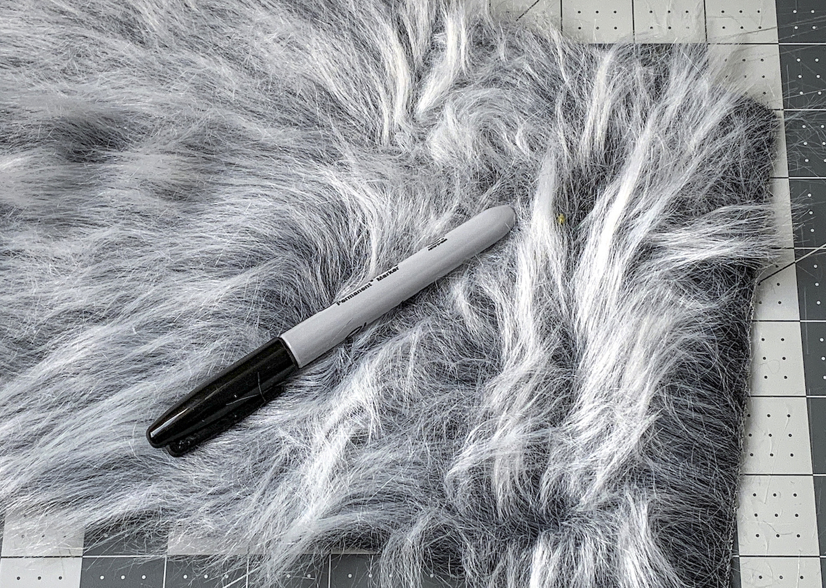 Piece of gray white faux fur with a marker on top