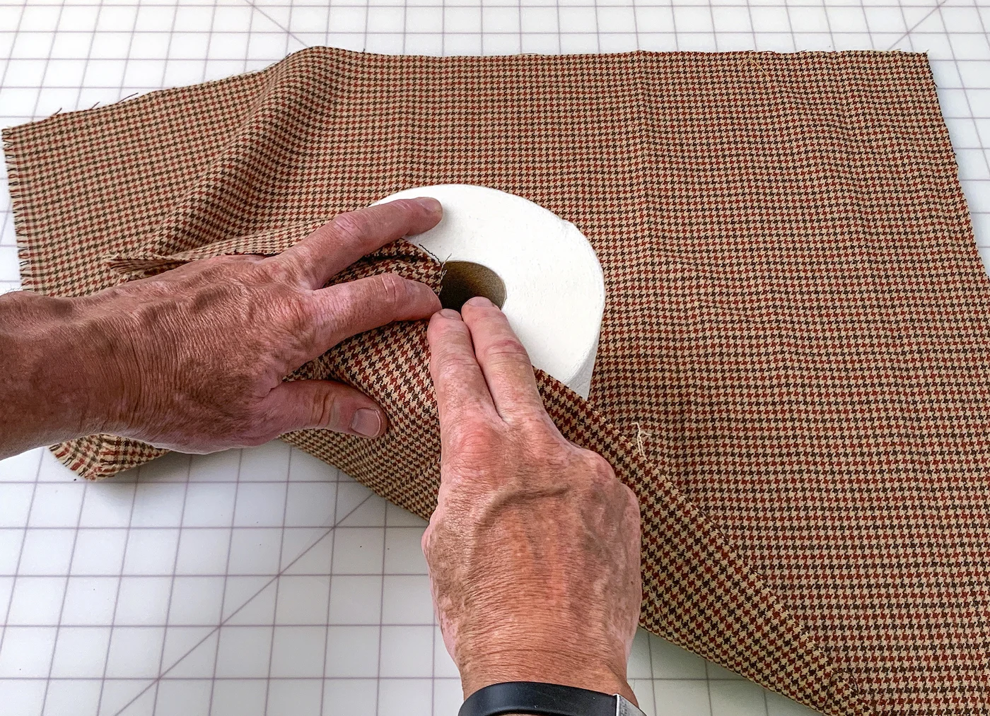 Beginning to tuck fabric into a roll of toilet paper