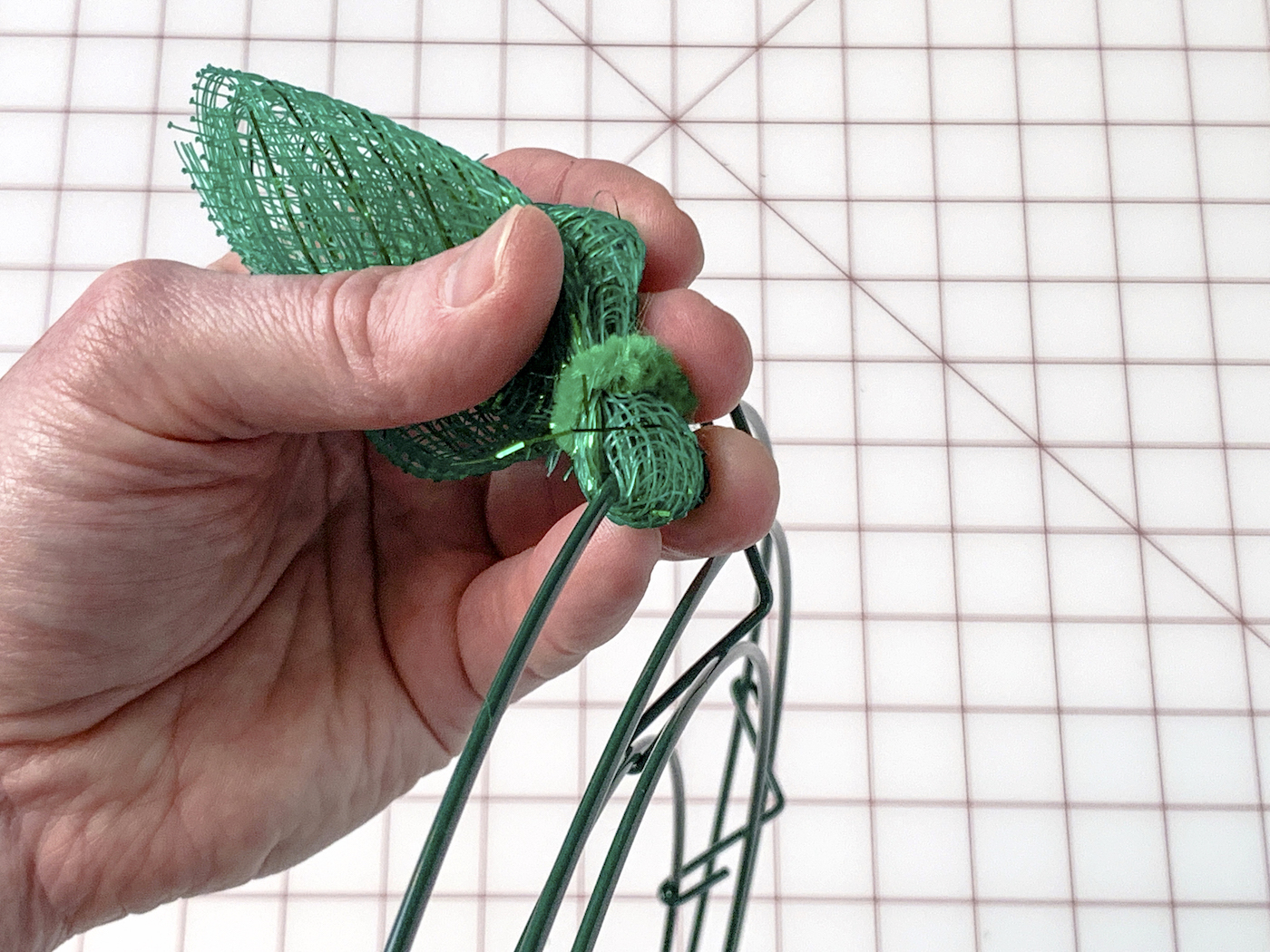 Piece of green deco mesh wrapped around the wreath wire and secured with a pipe cleaner