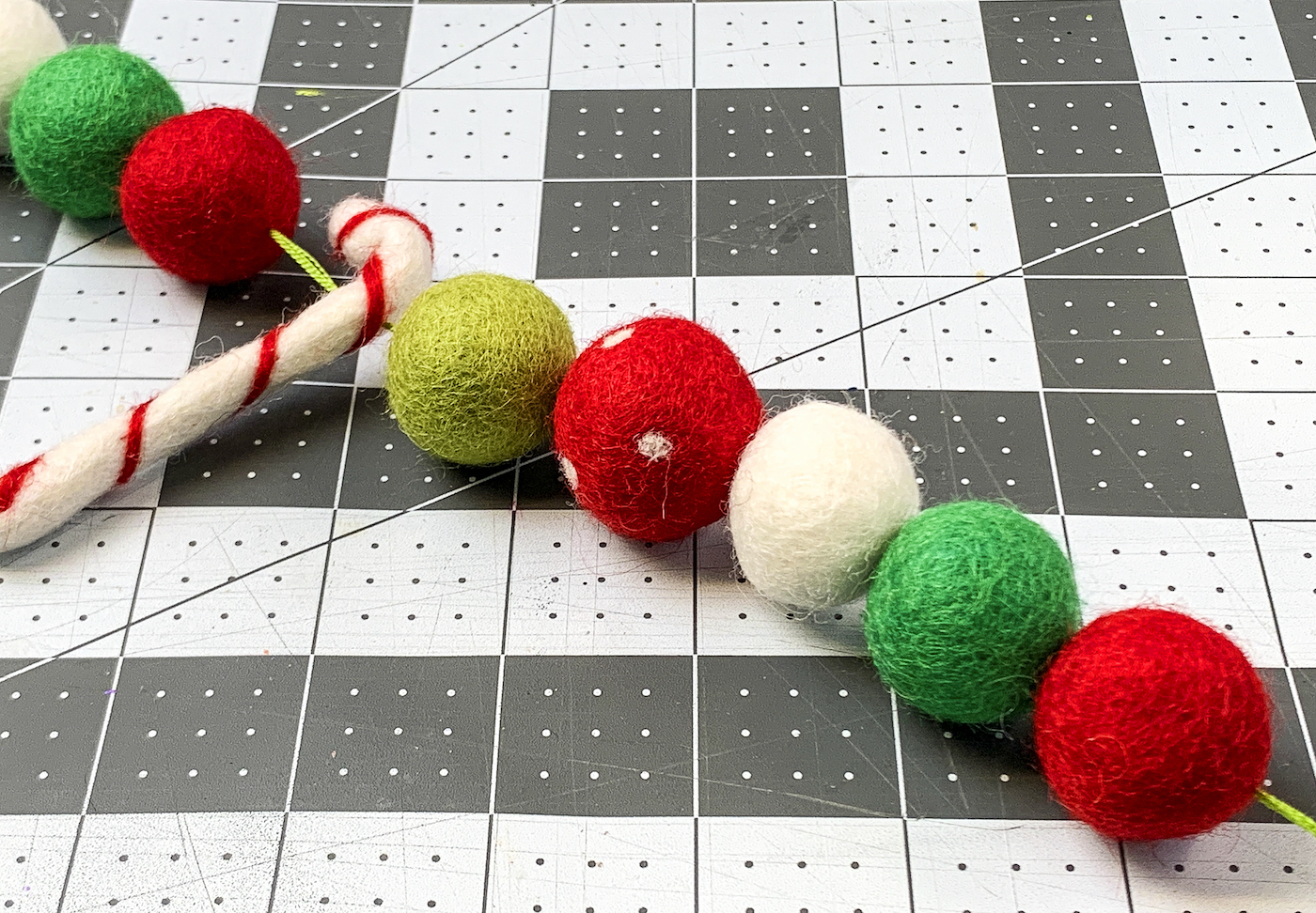 Felt balls and a felt candy cane strung onto embroidery floss