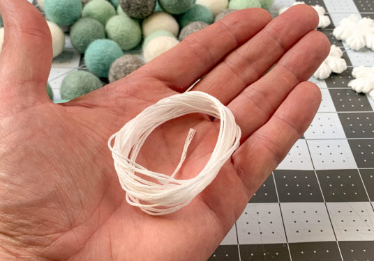 Hand holding white embroidery thread