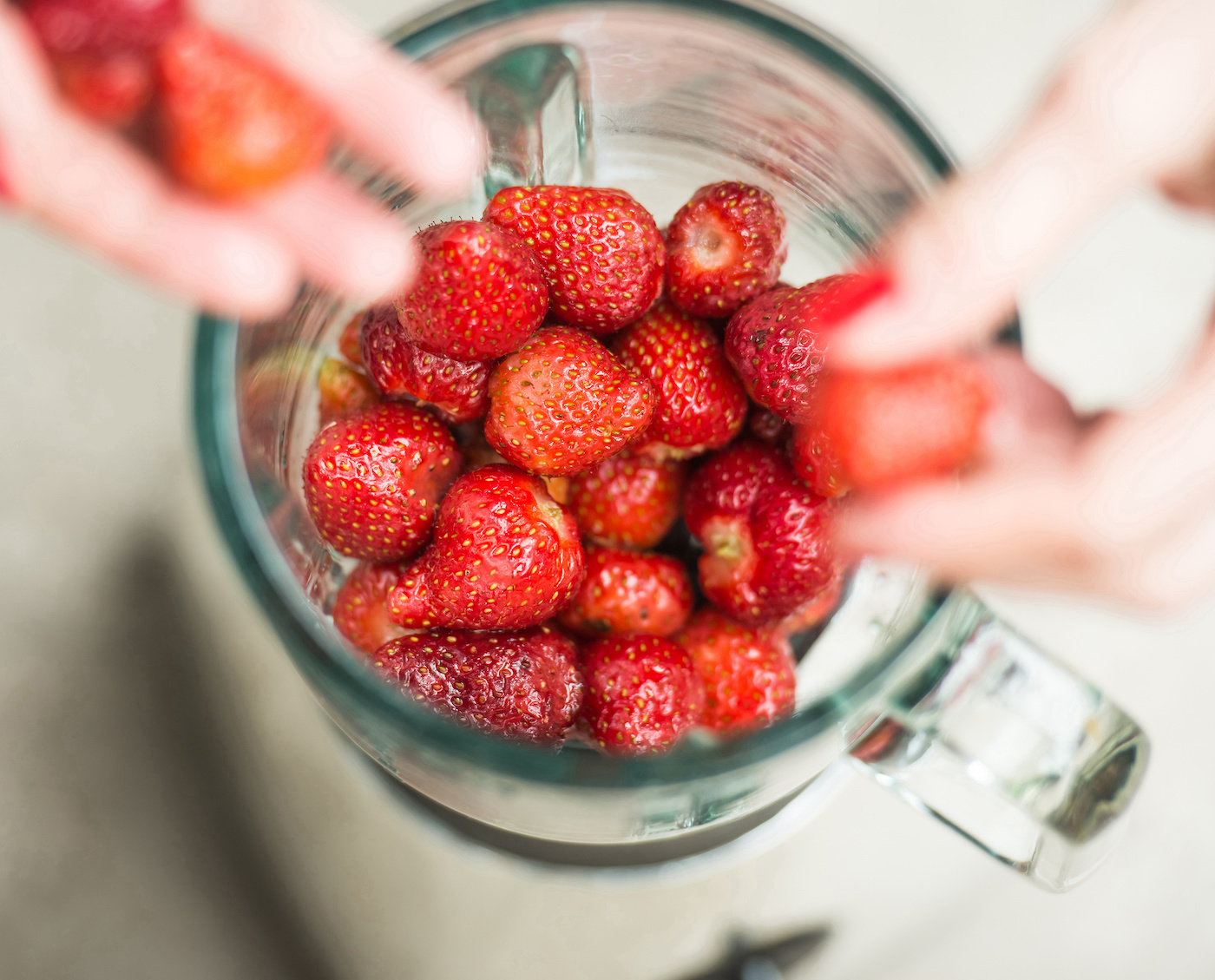 Hands-adding-strawberries-to-a-blender