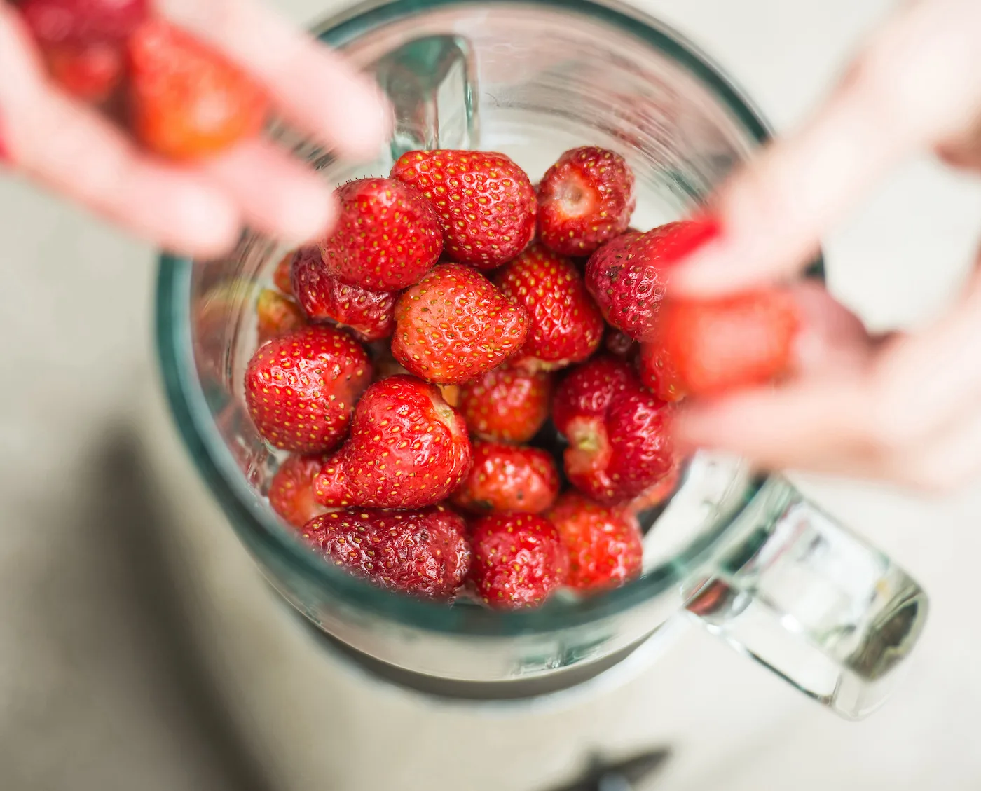 Hands-adding-strawberries-to-a-blender
