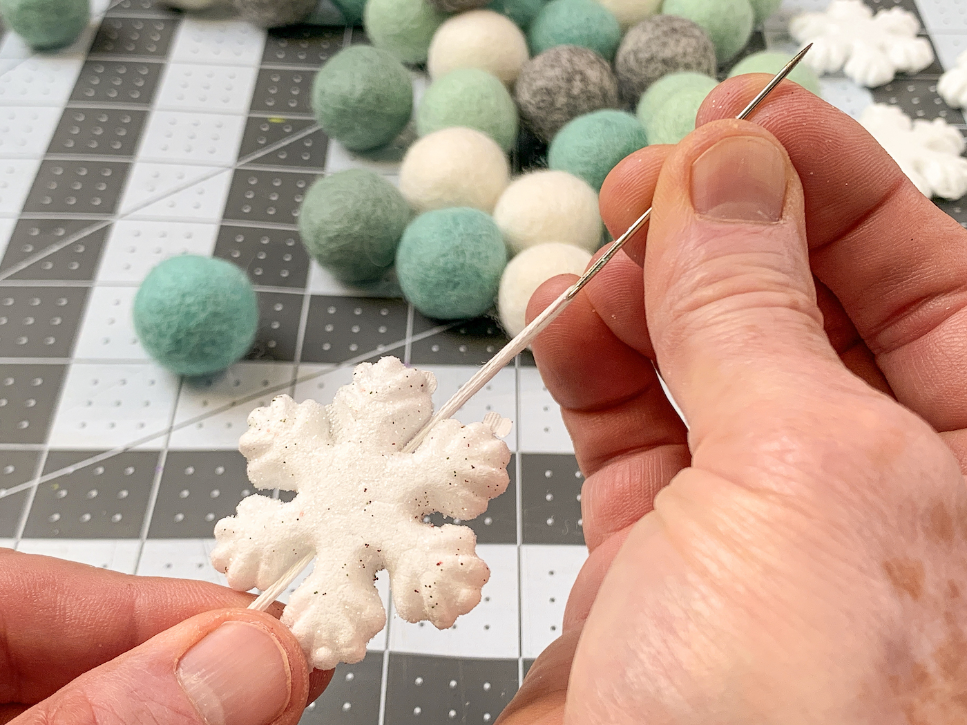 Stringing a foam snowflake onto floss