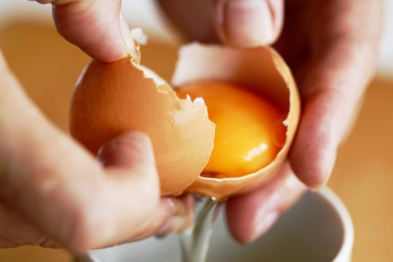 Two-hands-breaking-an-egg