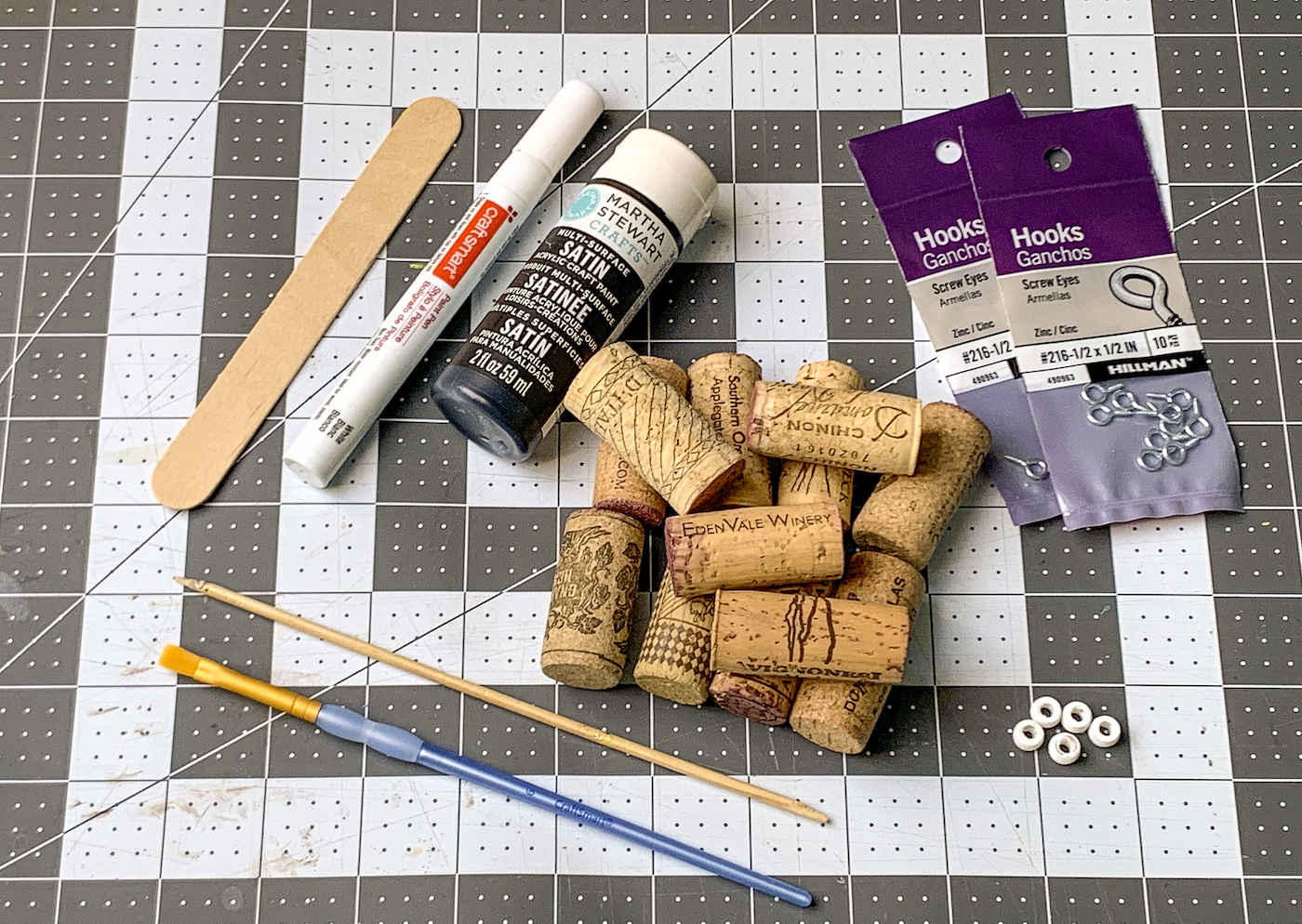 Wine corks, black paint, white paint pen, popsicle stick, paintbrushes, beads, and eye screws