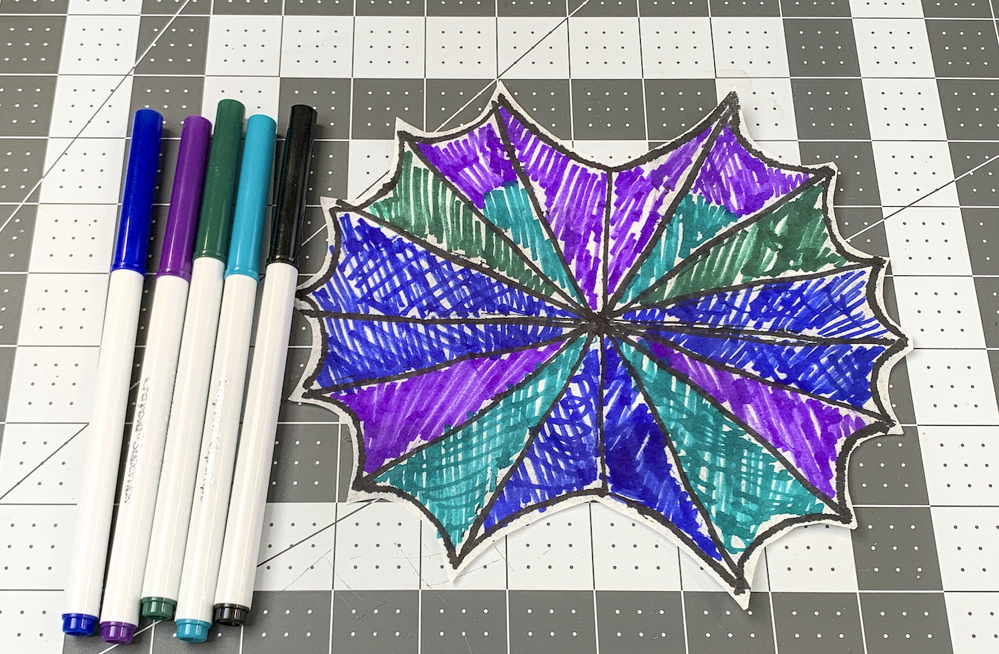 Black, purple, blue, and green markers with lines drawn on the coffee filter