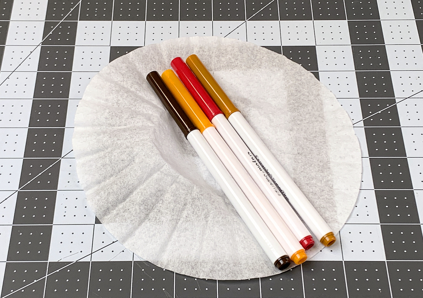 Four washable markers on top of a coffee filter