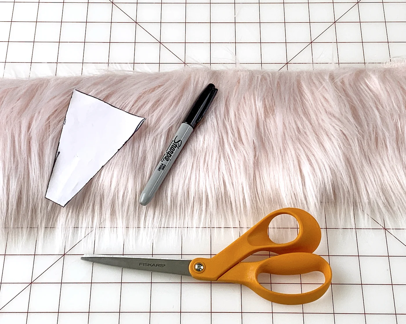 Pink faux fur, template, orange handled scissors, and a Sharpie