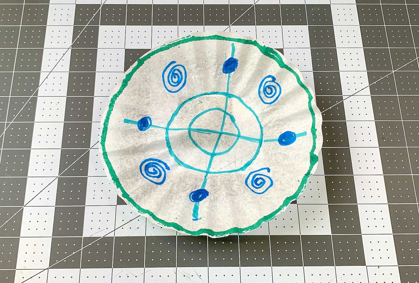 Coffee filter with marker lines drawn on it in green, blue, and aqua marker