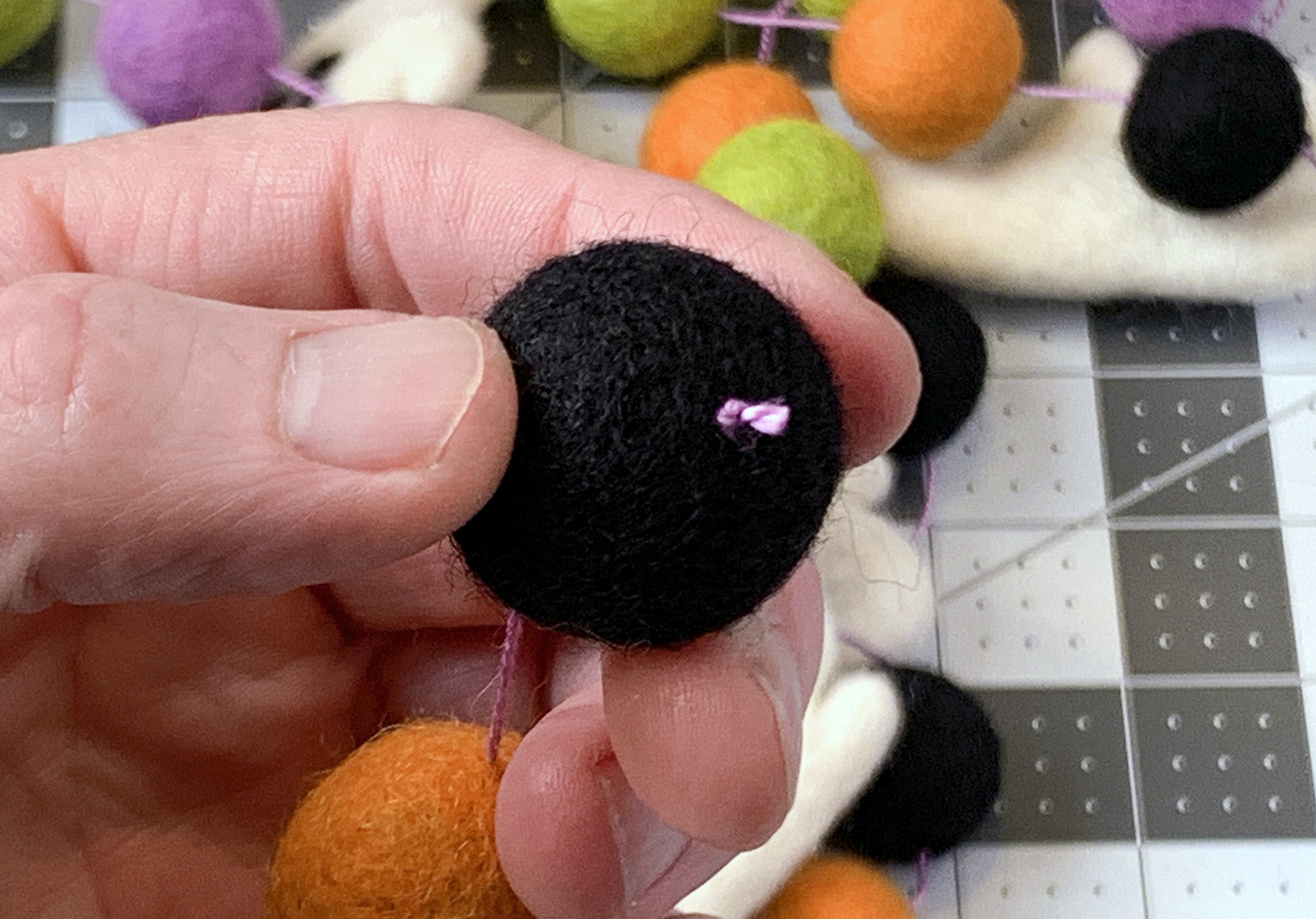 Felt black ball on embroidery floss with a knot at the end