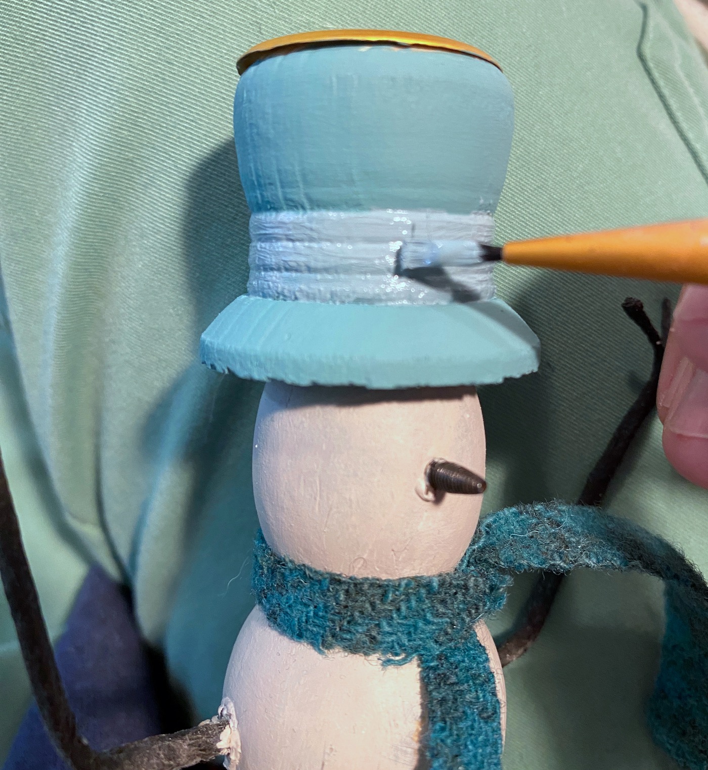Painting the band of the hat with light blue chalk paint