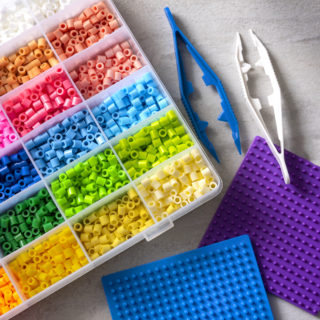 Perler beads in several colors, pegboards, and two sets of plastic tweezers
