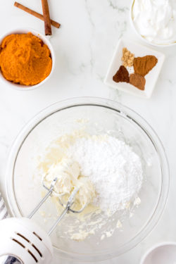 Beating cream cheese with the mixer while adding powdered sugar