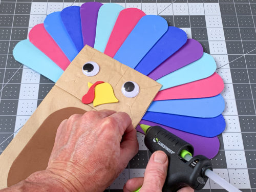 gluing the foam feathers to the paper bag