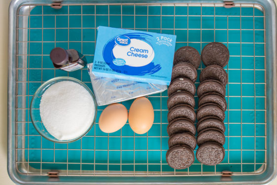 sugar, cream cheese, vanilla extract, eggs, and oreos on a wire rack