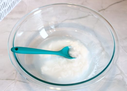 Glue and water being mixed together in a bowl with a spoon